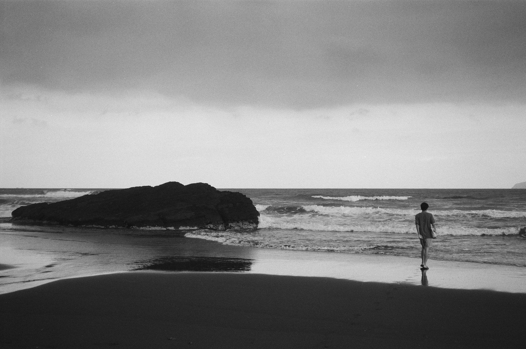 a man standing on a beach next to the ocean