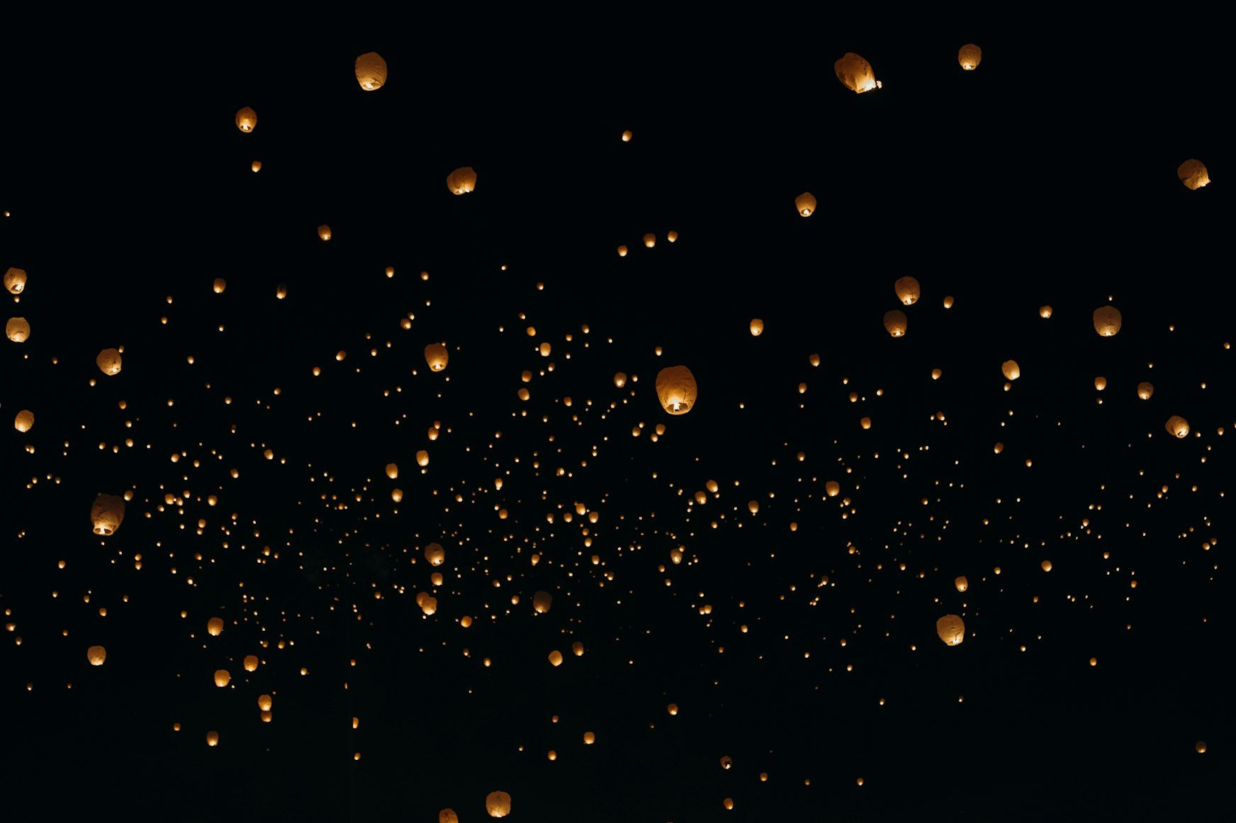a lot of lanterns floating in the air at night